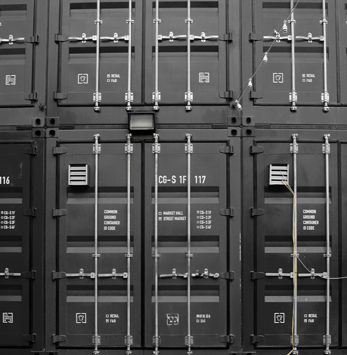 Stacked black cargo containers with identification markings, featuring a utilitarian design